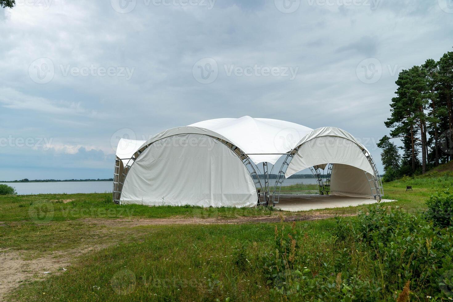Canopy structure sits near a tranquil lake under cloudy skies photo