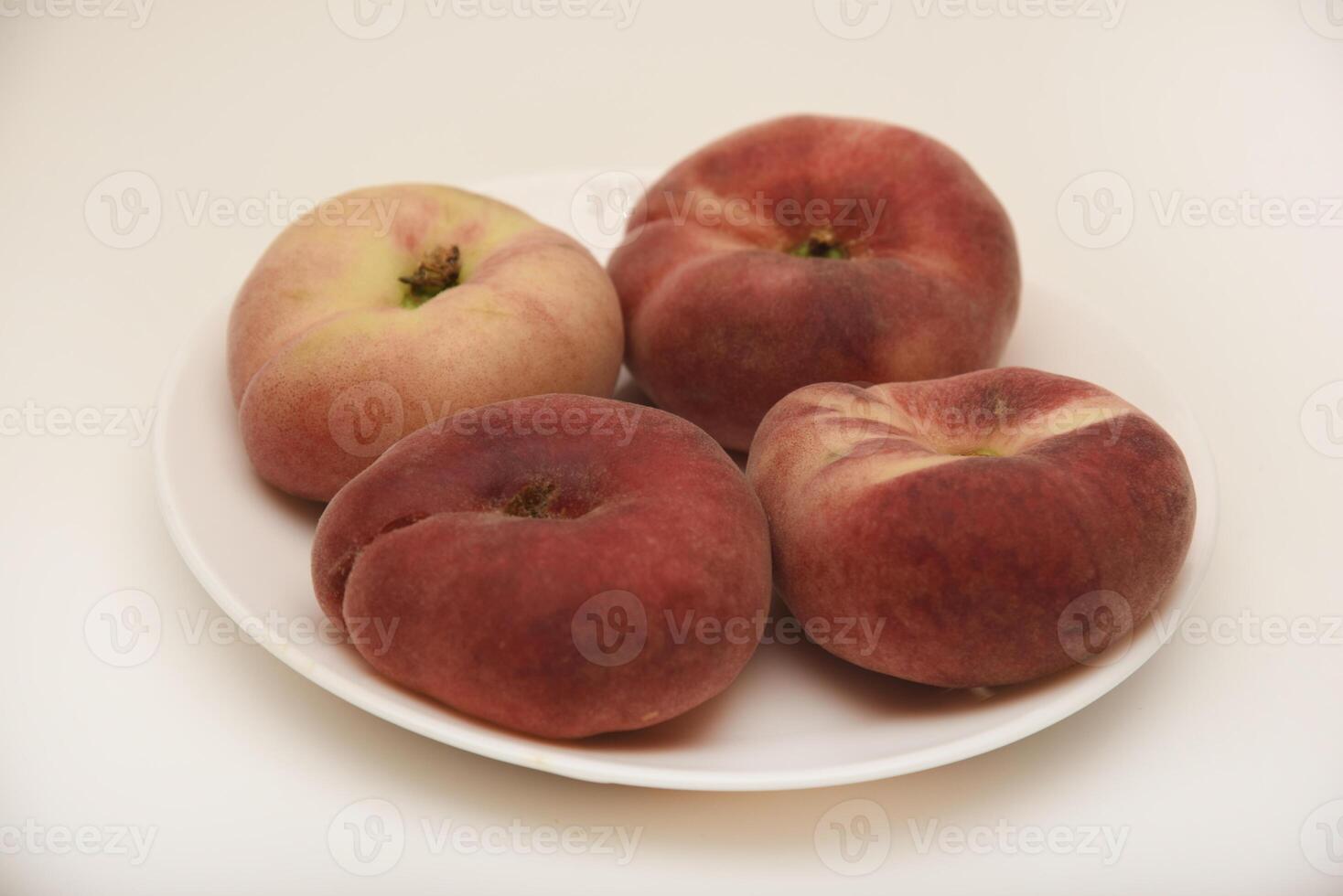 Flat peaches on a white plate. Delicious yellow peaches. photo