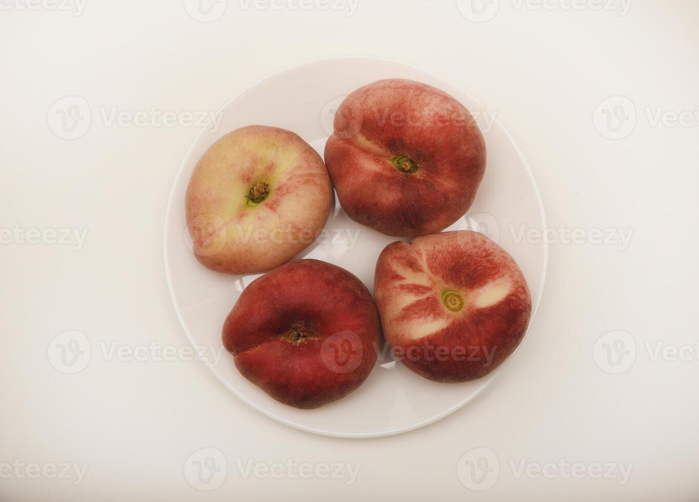 Flat peaches on a white plate. Delicious yellow peaches. photo