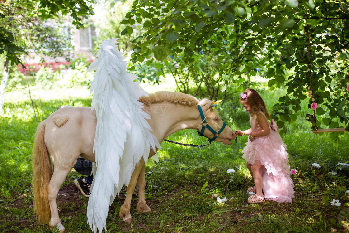 Cheerful cute girl playing and hugging magical unicorn. photo