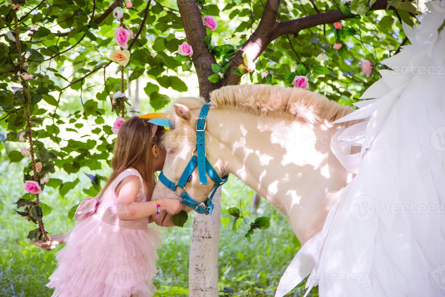 Cheerful cute girl playing and hugging magical unicorn. photo