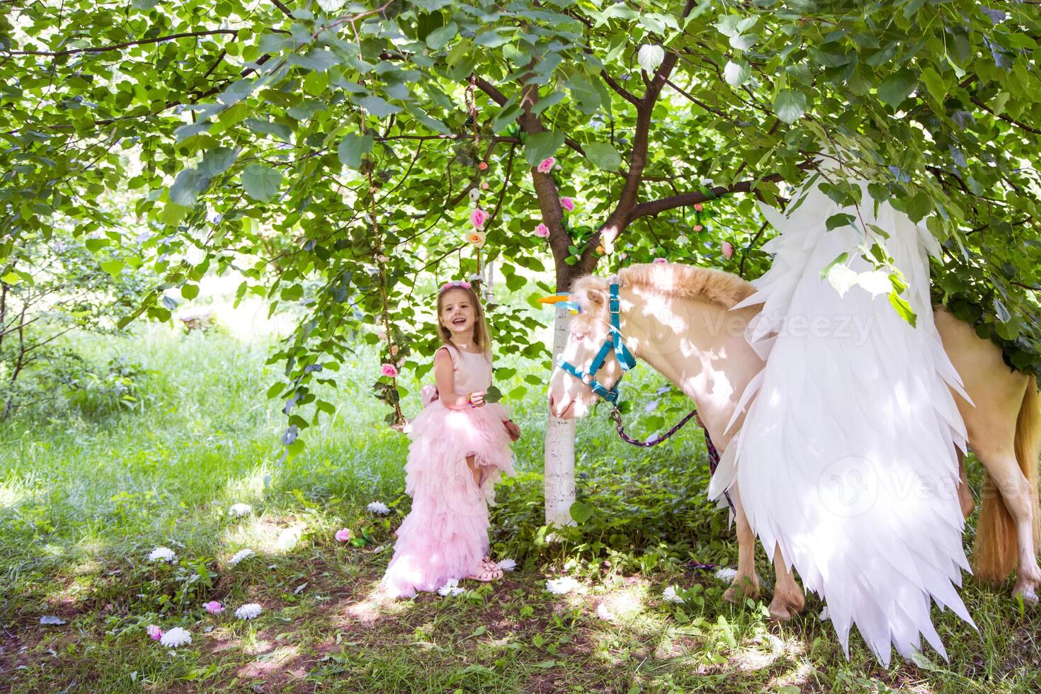 Cheerful cute girl playing and hugging magical unicorn. photo