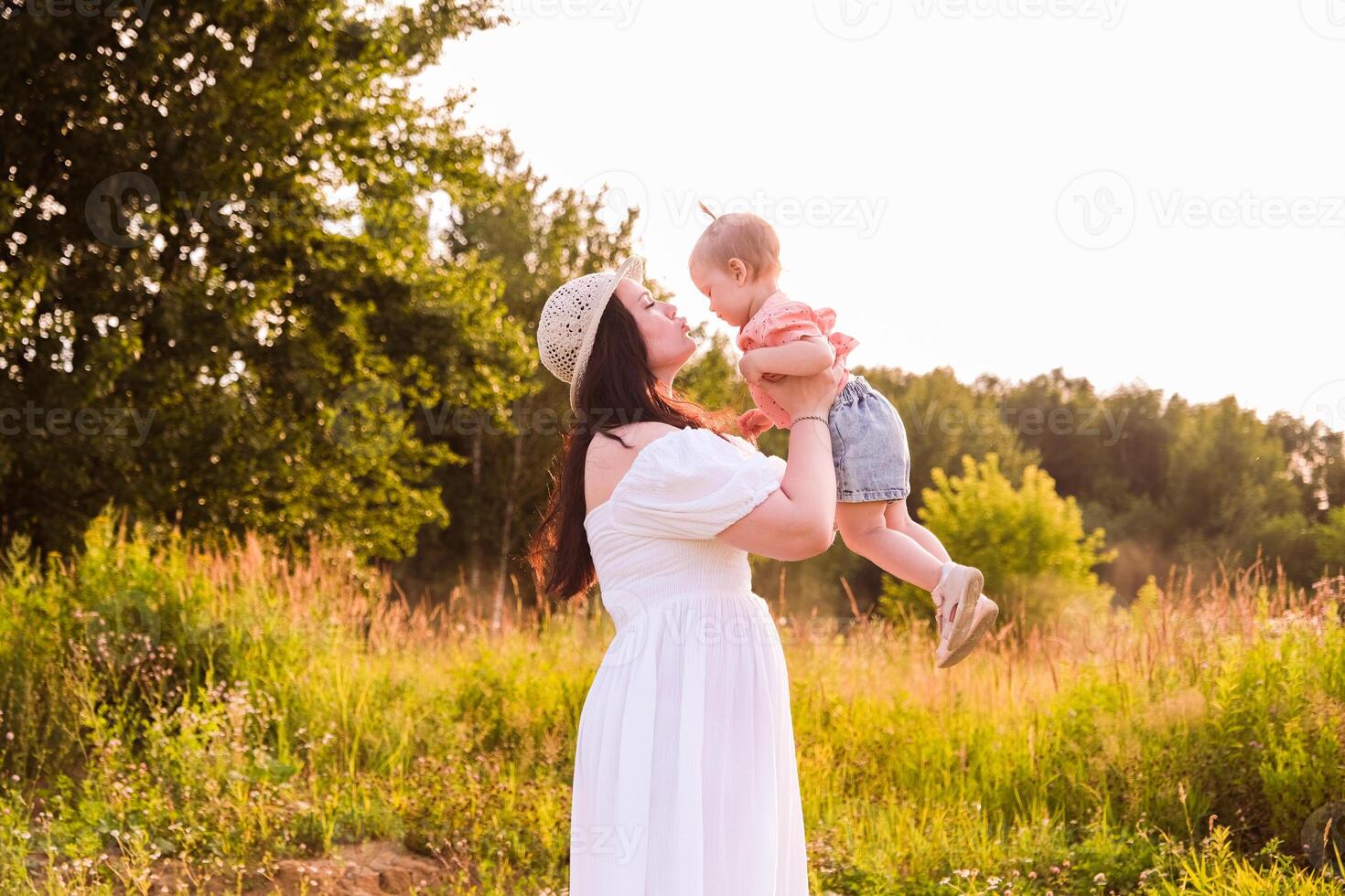Lifestyle mother and child in casual clothes playing together in chamomile field photo