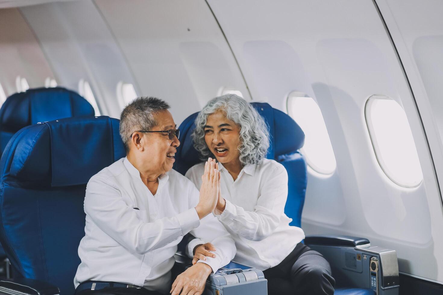 A mature couple enjoys a plane ride sitting near the window. They looked out into the sky. Immerse yourself in the scenery and excitement of the journey. To create precious memories together photo