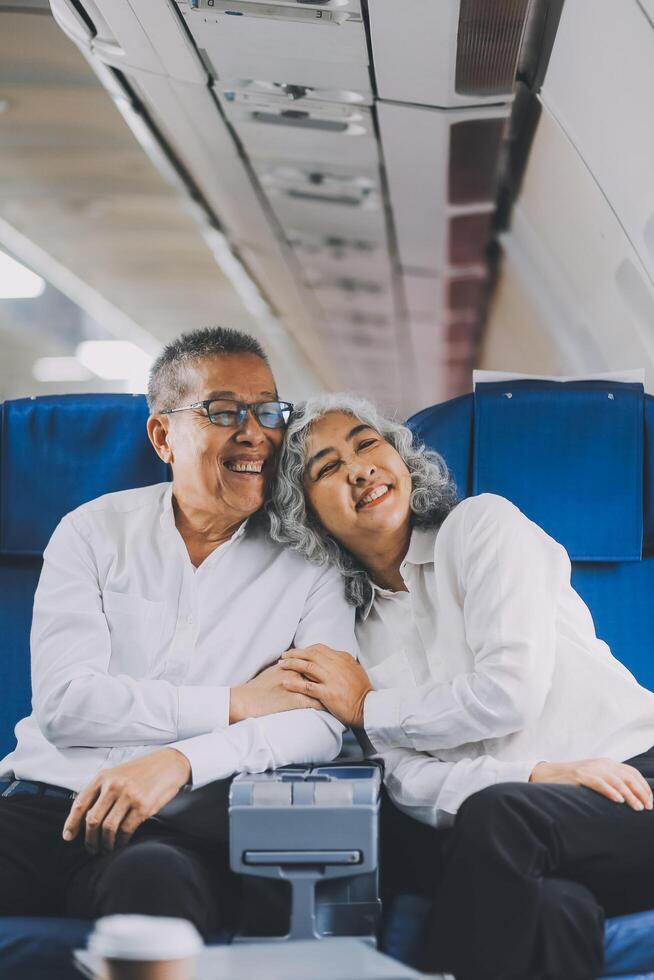 A mature couple enjoys a plane ride sitting near the window. They looked out into the sky. Immerse yourself in the scenery and excitement of the journey. To create precious memories together photo