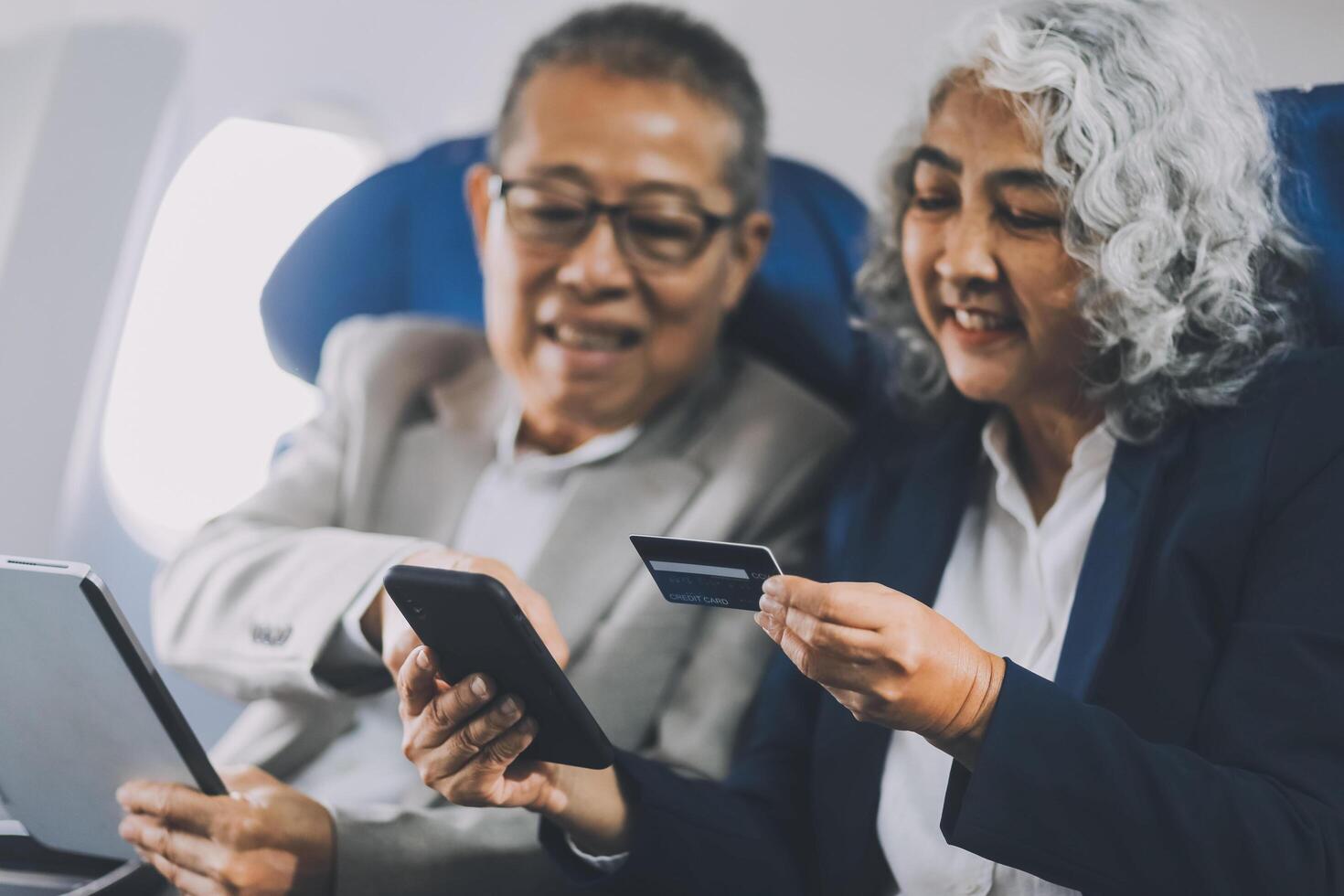 A mature couple enjoys a plane ride sitting near the window. They looked out into the sky. Immerse yourself in the scenery and excitement of the journey. To create precious memories together photo