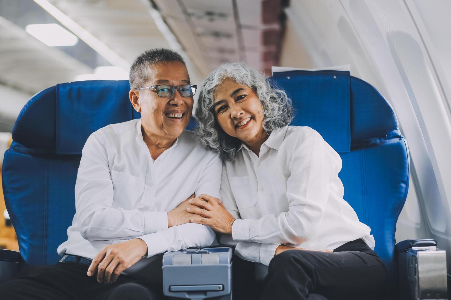 A mature couple enjoys a plane ride sitting near the window. They looked out into the sky. Immerse yourself in the scenery and excitement of the journey. To create precious memories together photo