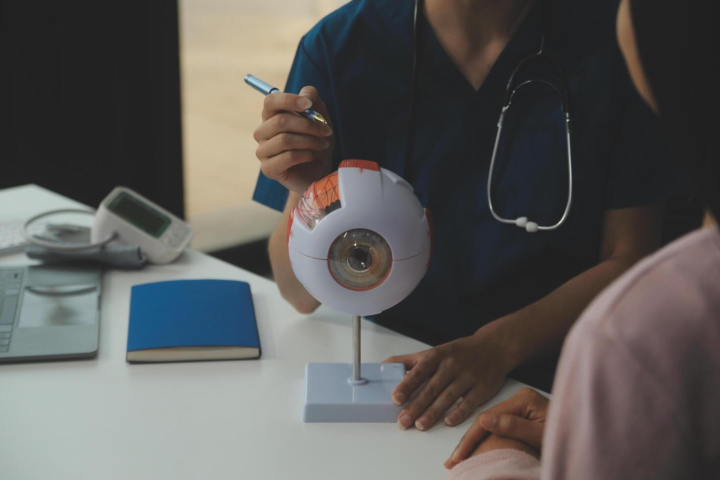 Ophthalmologist doctor in clinic, part of eye model on desk, oculus sample photo
