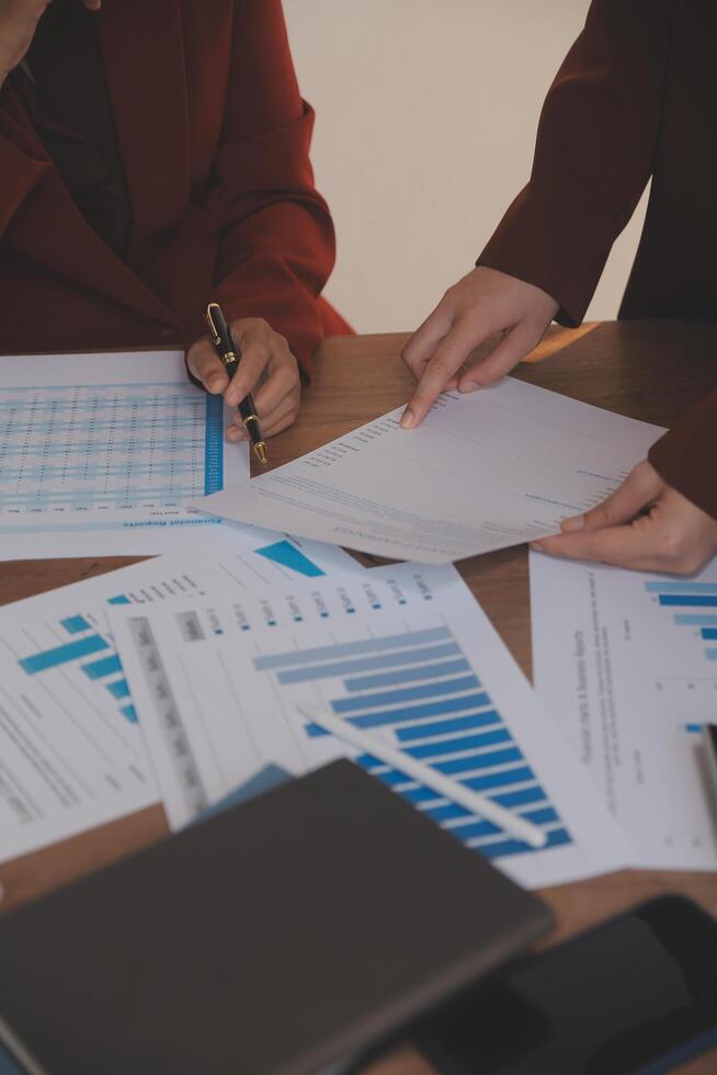 Group of confident business people point to graphs and charts to analyze market data, balance sheet, account, net profit to plan new sales strategies to increase production capacity. photo