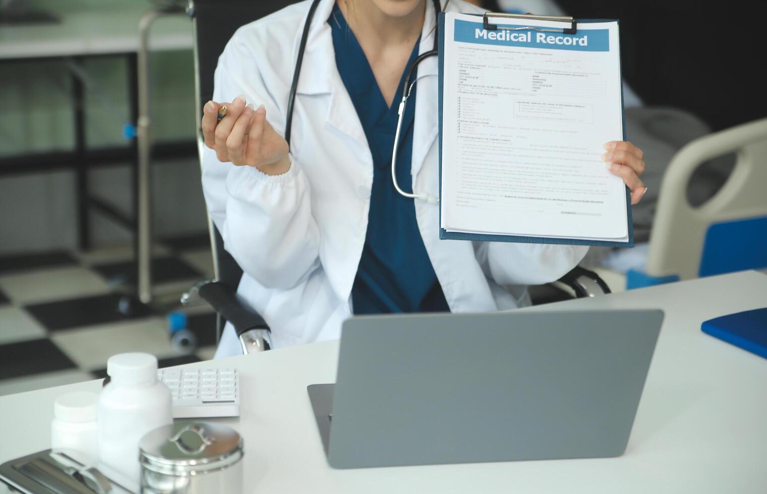 A beautiful and professional Asian female doctor is working on her medical cases on her laptop or making a call medical consultation with a patient while sitting in her office. photo