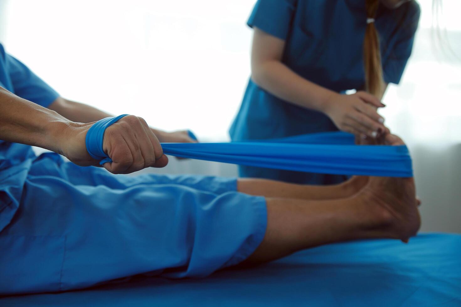 Professional orthopedist examining the little patient's leg in the clinic. Patient at the physiotherapy doing physical exercises with his therapist photo