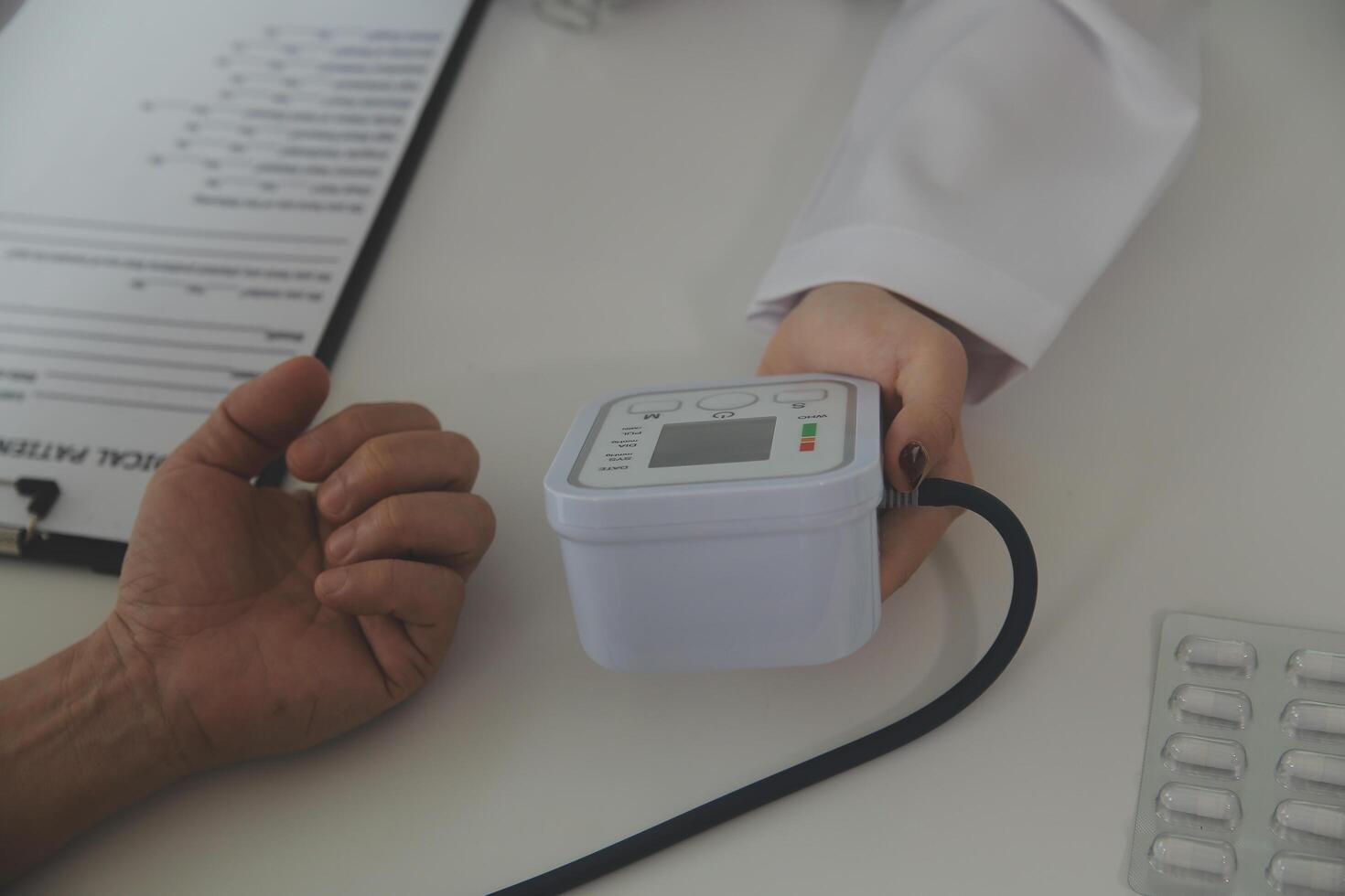 Doctor using sphygmomanometer with stethoscope checking blood pressure to a patient in the hospital. photo
