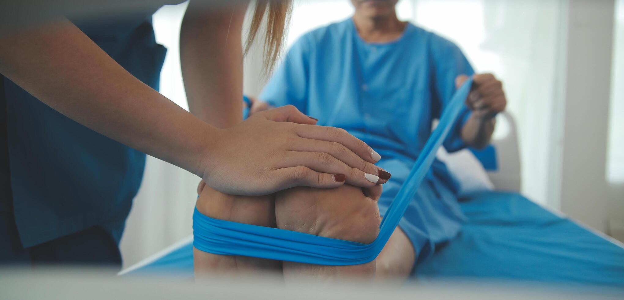 Professional orthopedist examining the little patient's leg in the clinic. Patient at the physiotherapy doing physical exercises with his therapist photo