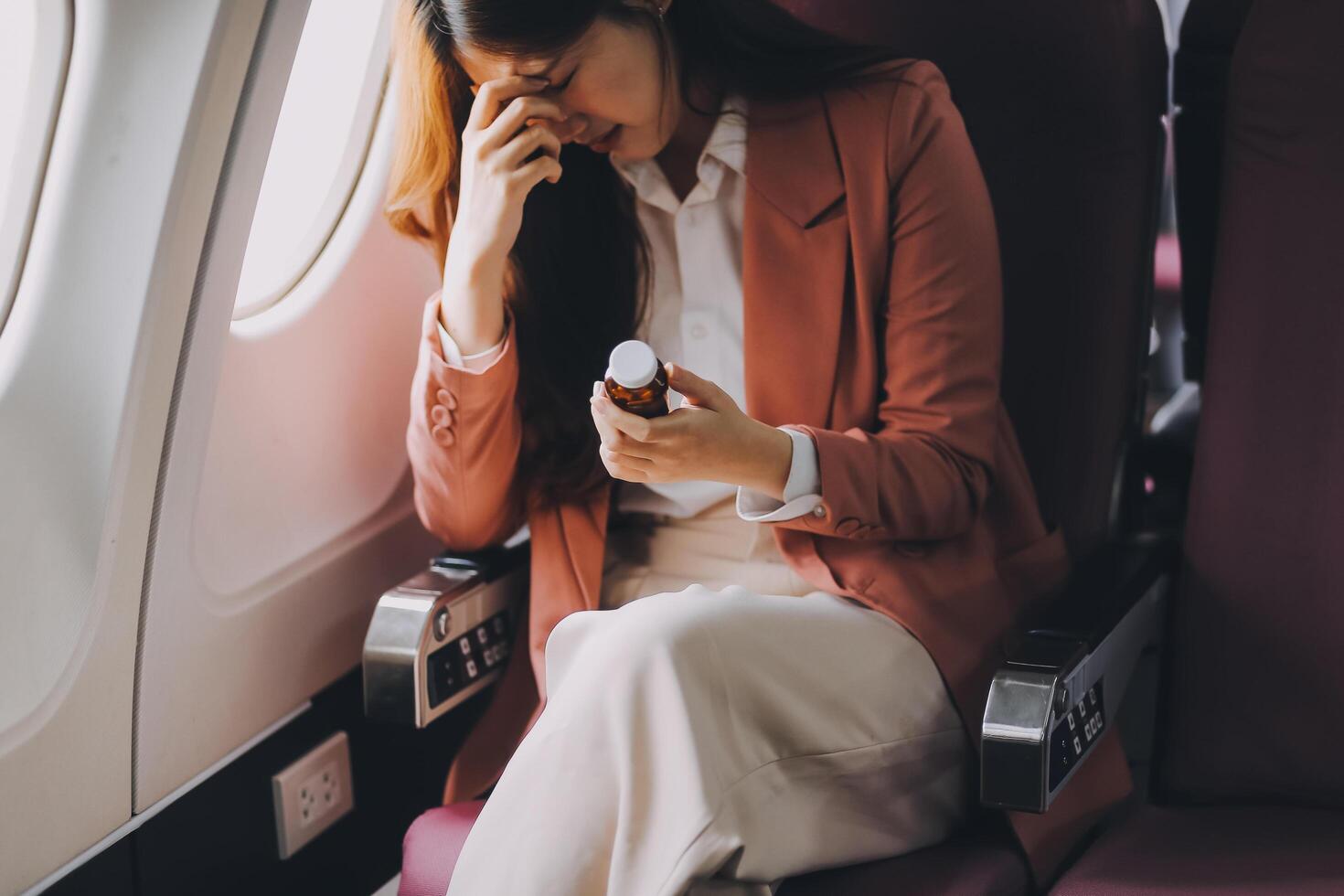 Tired asian woman with headache feeling sick while sitting in the airplane , Passengers near the window. photo