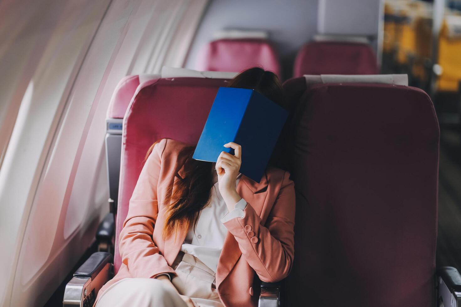 Tired asian woman with headache feeling sick while sitting in the airplane , Passengers near the window. photo