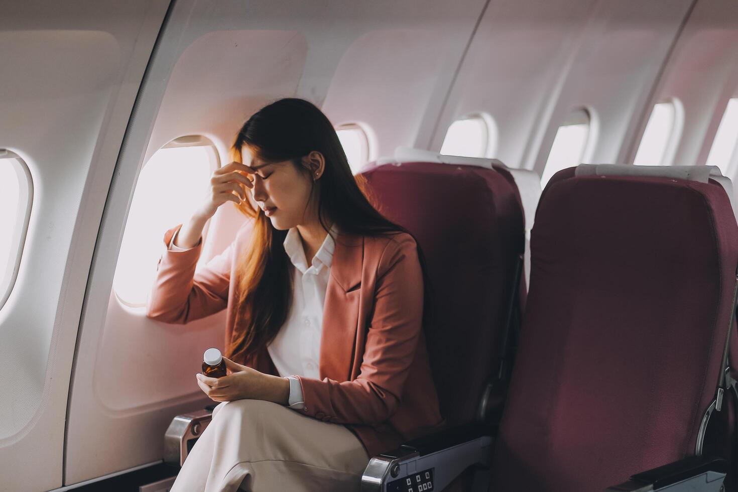 Tired asian woman with headache feeling sick while sitting in the airplane , Passengers near the window. photo