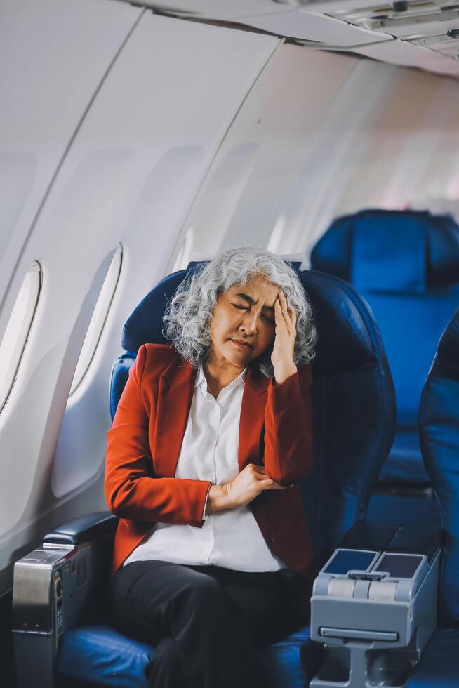 Mature with headache with nausea feeling sick while sitting in the airplane , Passengers near the window. photo