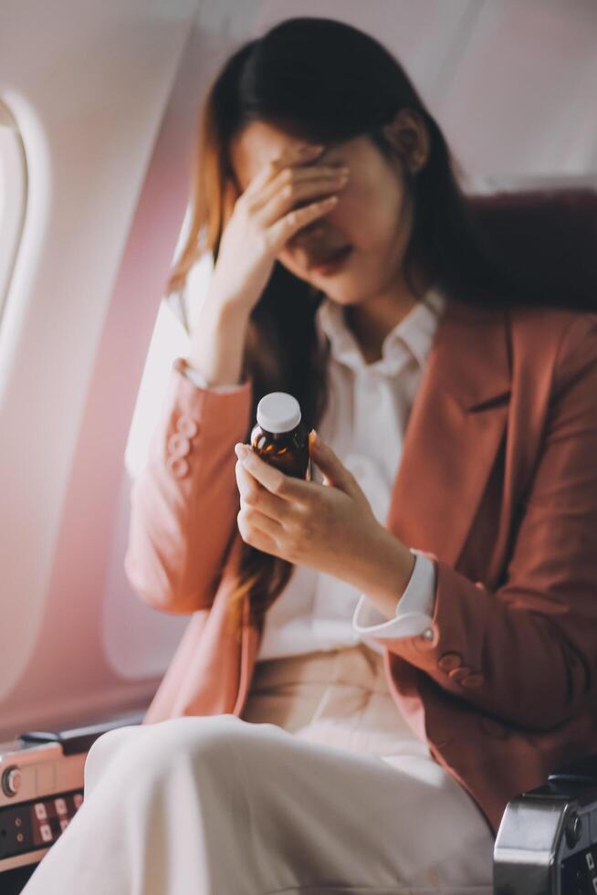 Tired asian woman with headache feeling sick while sitting in the airplane , Passengers near the window. photo