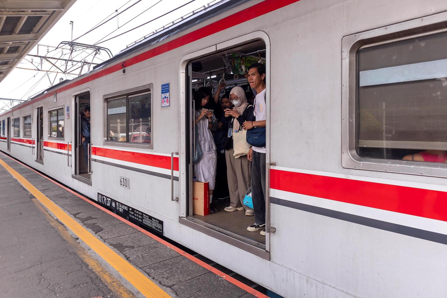 Jakarta, Indonesia, 2024 - The commuter line train stops at the station. Doors open and carriages full of passengers. Mass public transportation in Jakarta. photo