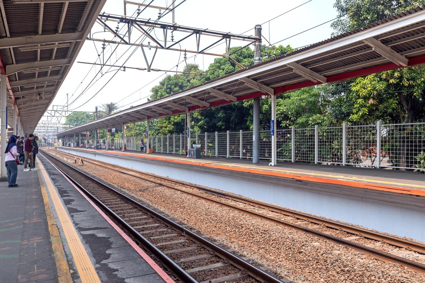 Jakarta, Indonesia, 2024 - Passengers waiting for the train to arrive at the station. View of a commuter line train platform in Jakarta. photo