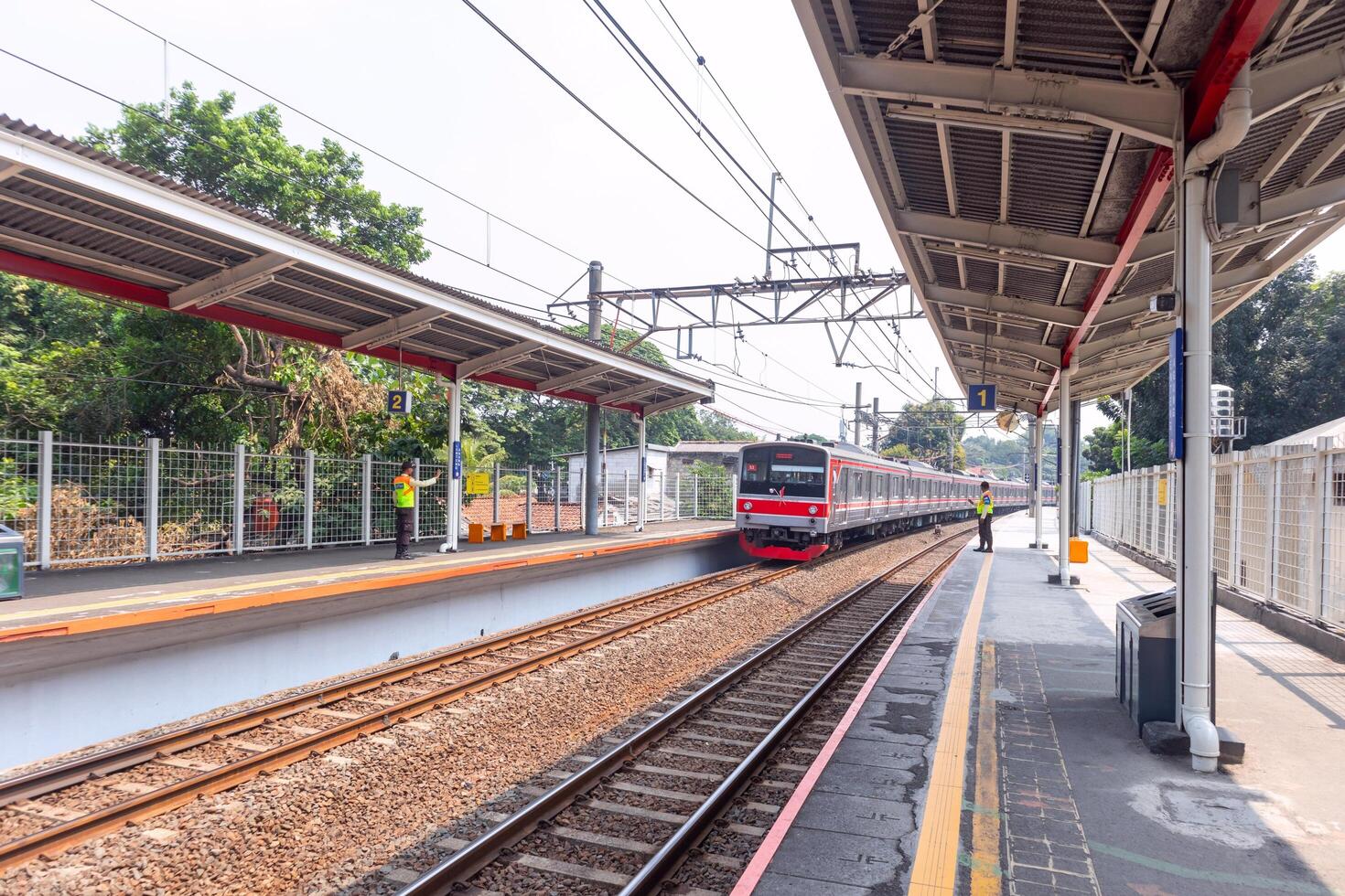 Jakarta, Indonesia, 2024 - A commuter train arrives at the station and two security guards are on the platform. photo