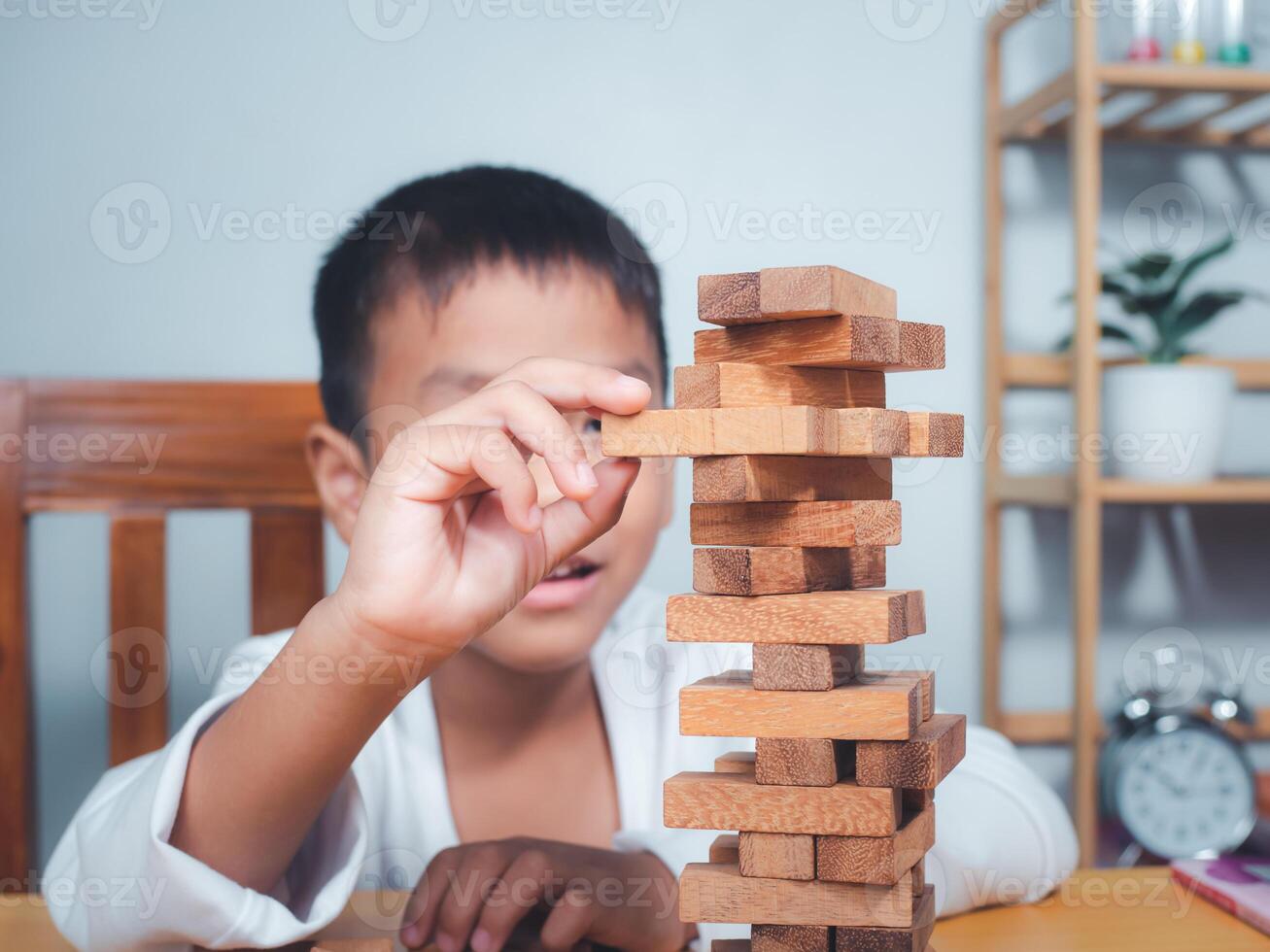 Cheerful Asian boy playing with wooden building blocks Jenga, Having fun and learning creativity, smart kid concept, wooden block Planning, Risk and strategy of project management in business. photo