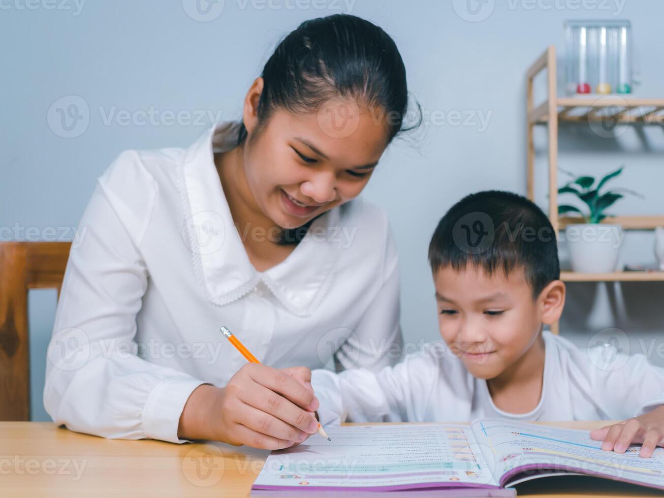 Teacher or mother helping boy writing lesson and learning to write, Female tutor helping little elementary school boy with homework during individual lesson at home, Education home school concept. photo