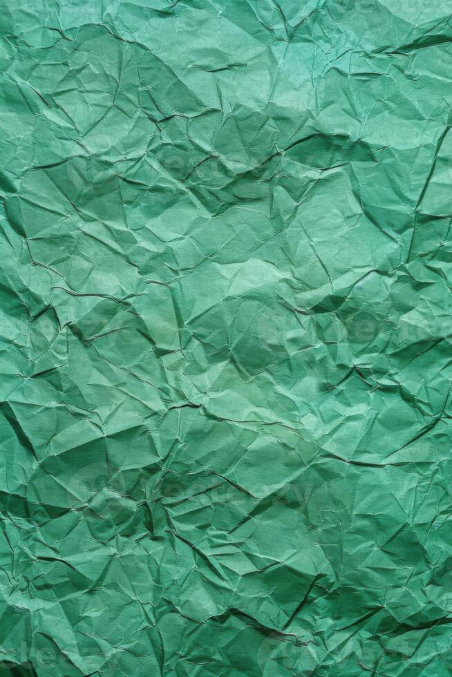 Crumpled green paper texture with varying shades and deep folds. Abstract background. photo