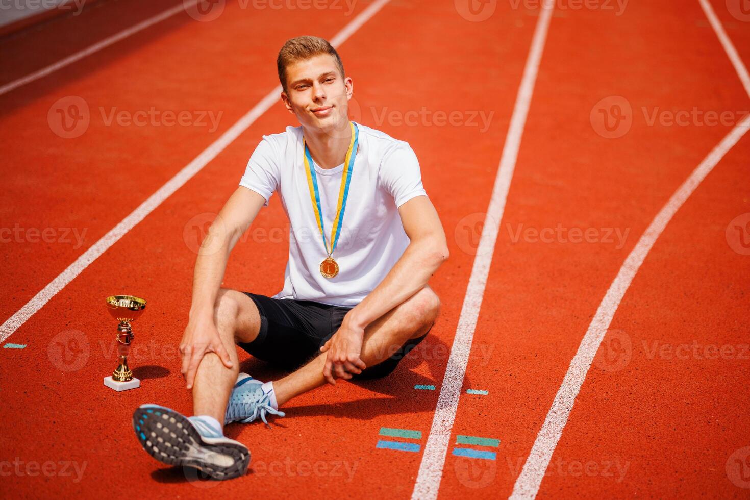 Young athlete with medal and trophy on track photo
