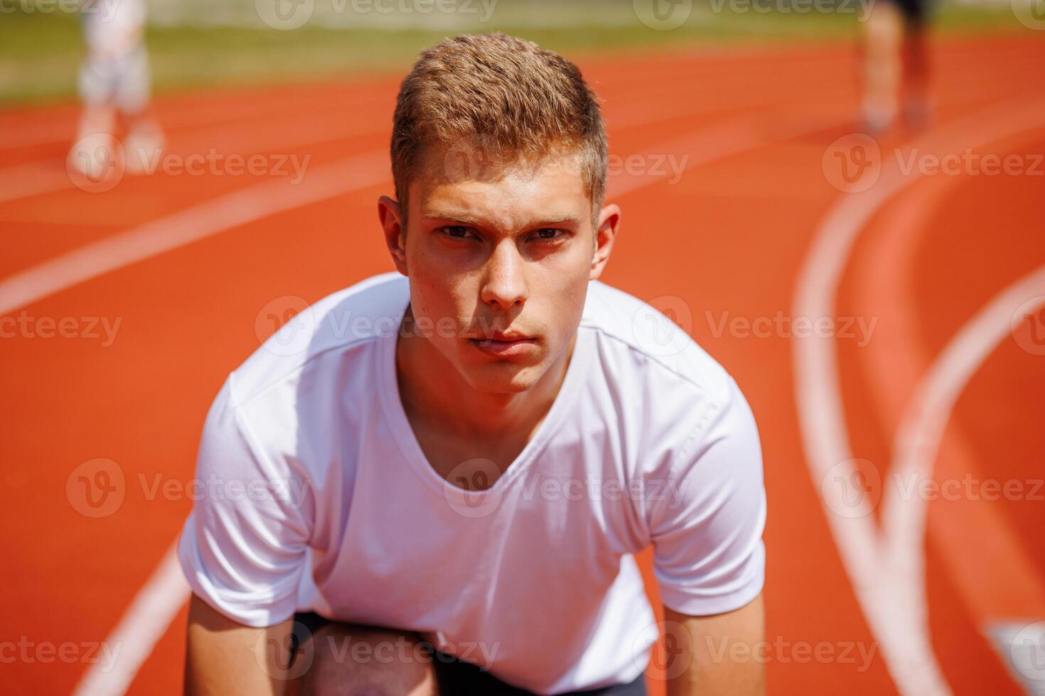 Young male athlete preparing for a race on a running track photo