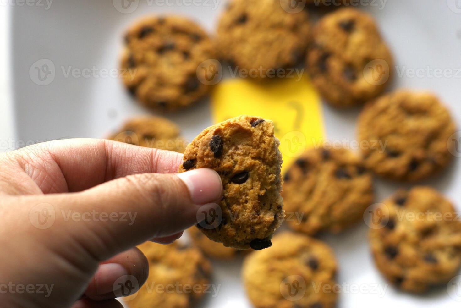 A person taking a choco chip cookie from the plate photo