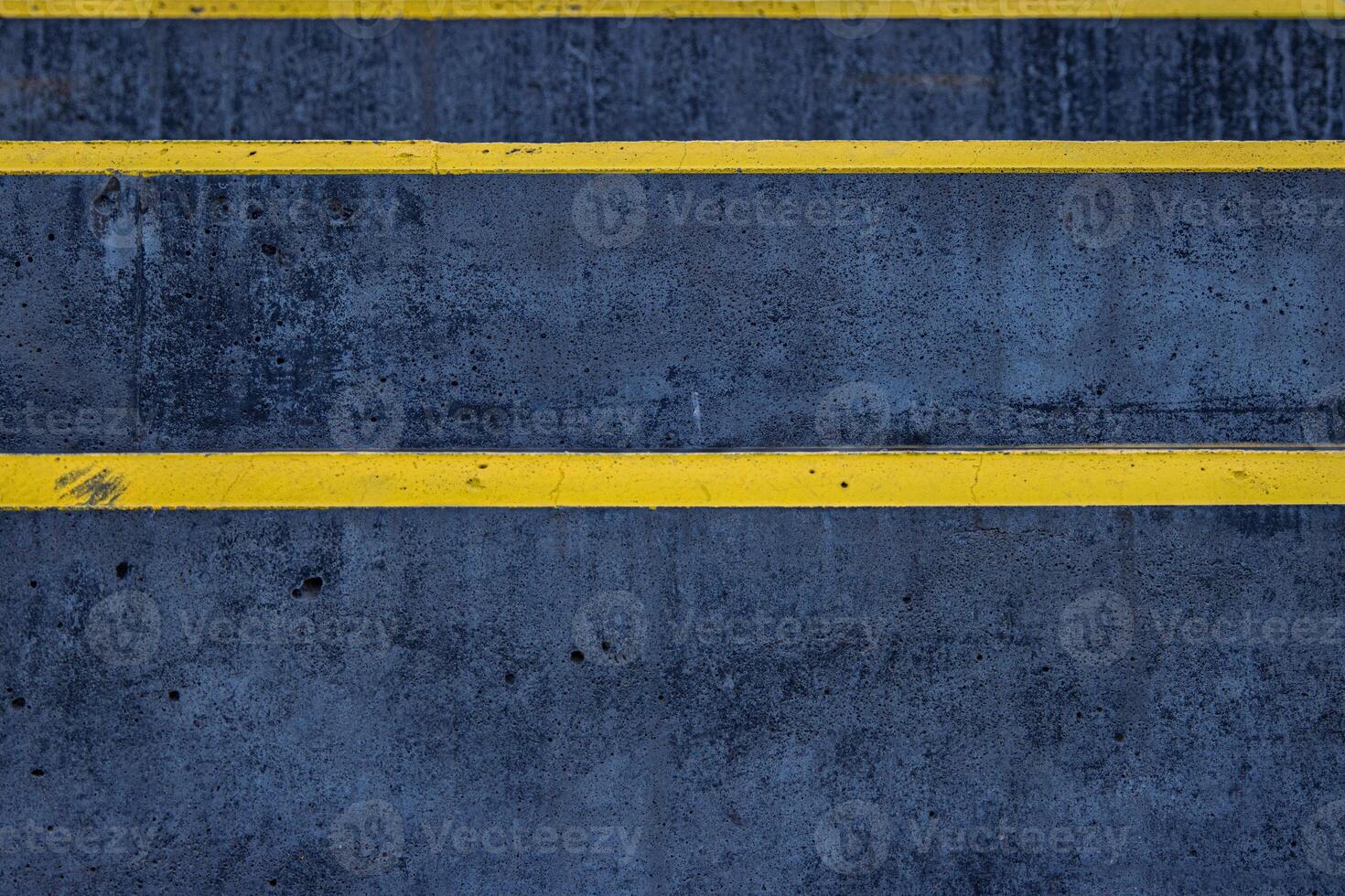 Closeup of a textured asphalt road with weathered yellow stripes on a rough gray pavement, great for use in street photography, urban design, or traffic-related visuals. Copy space photo