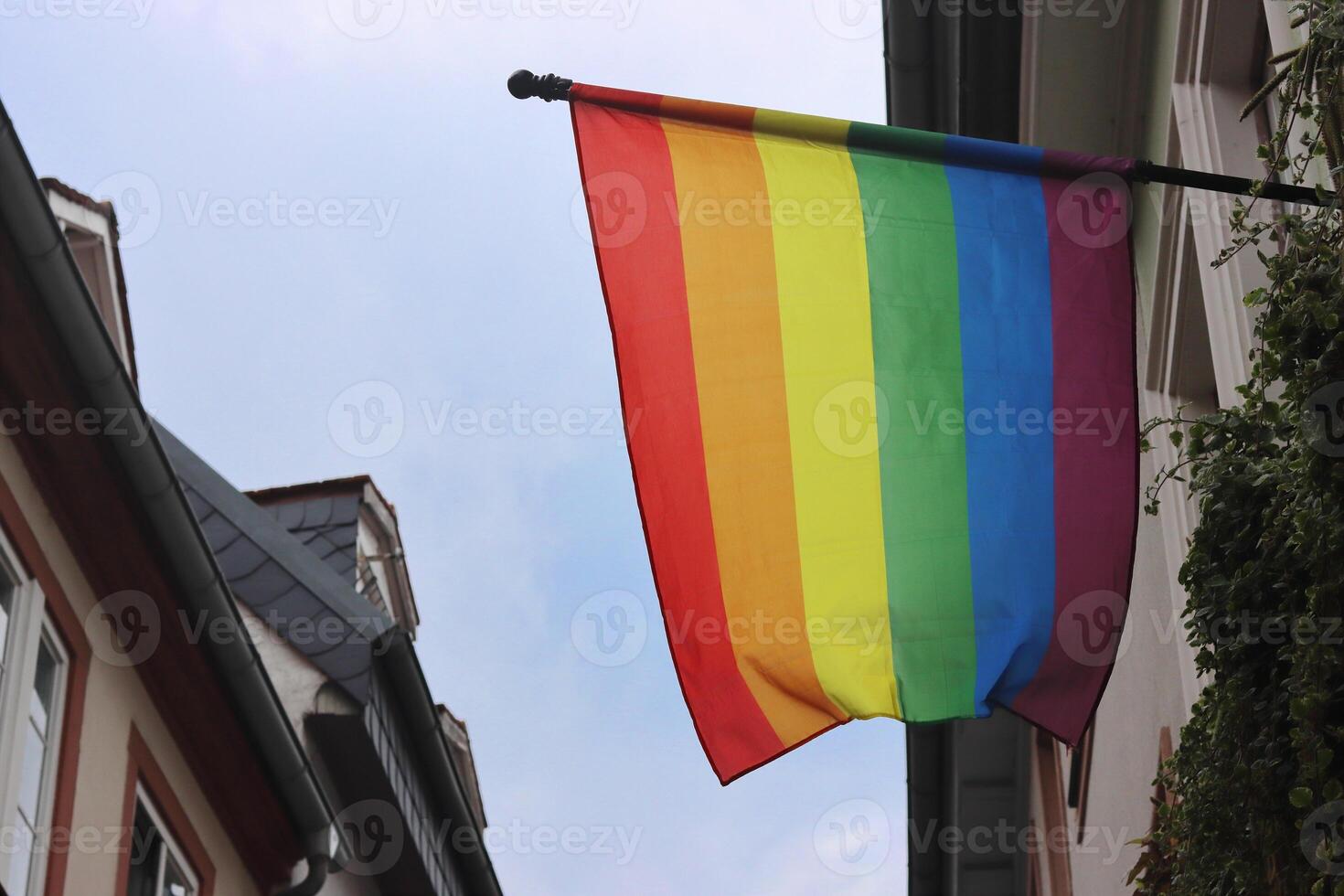 Rainbow Flag in the center of Heidelberg, Germany. Buildings and cloudy sky on the background photo