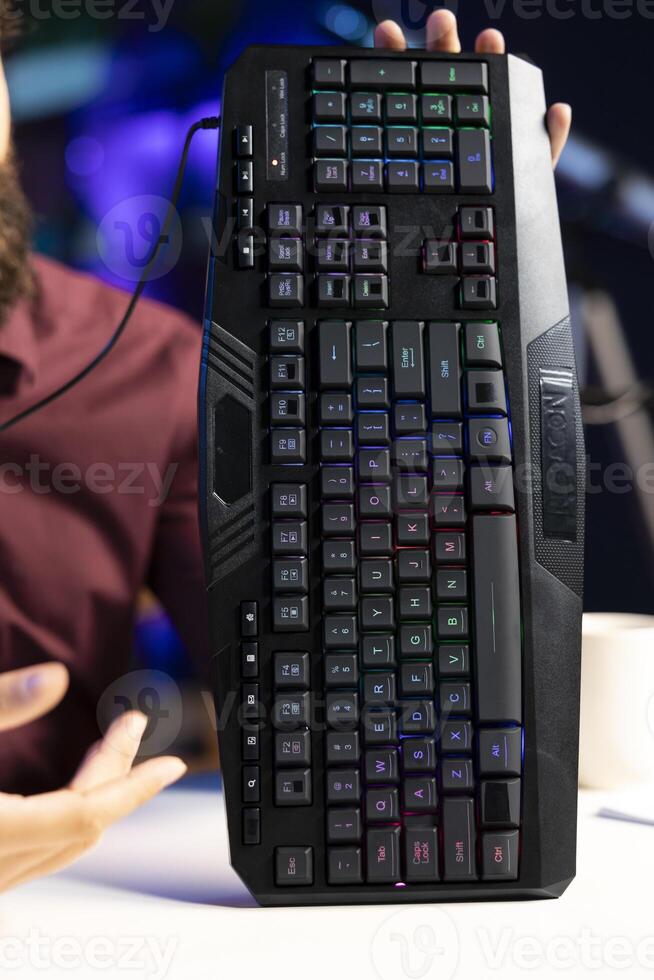 Close up shot of gaming keyboard presented by influencer filming review in personal studio. RGB lit computer peripheral showcased by content creator for viewers of technology channel photo