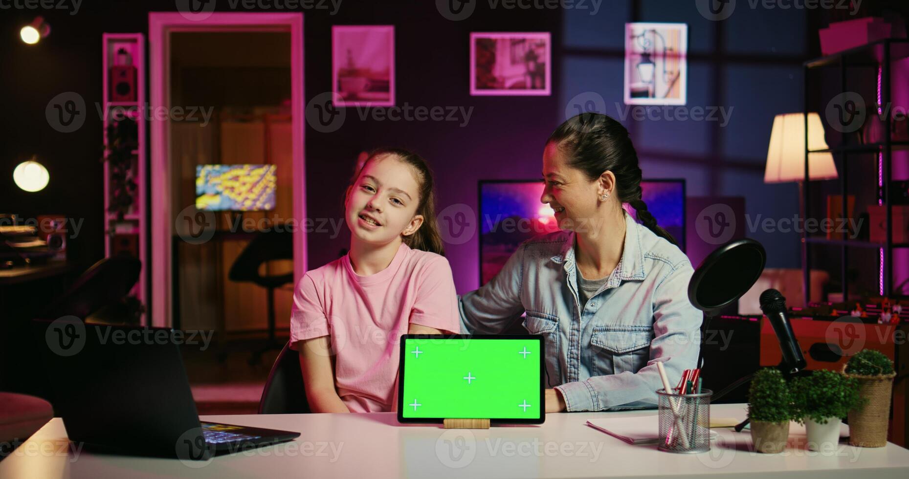 Cute child influencer in home studio using recording gear to record review of mockup tablet. Young girl online show host filming electronics haul, presenting chroma key device for gen Z fans photo