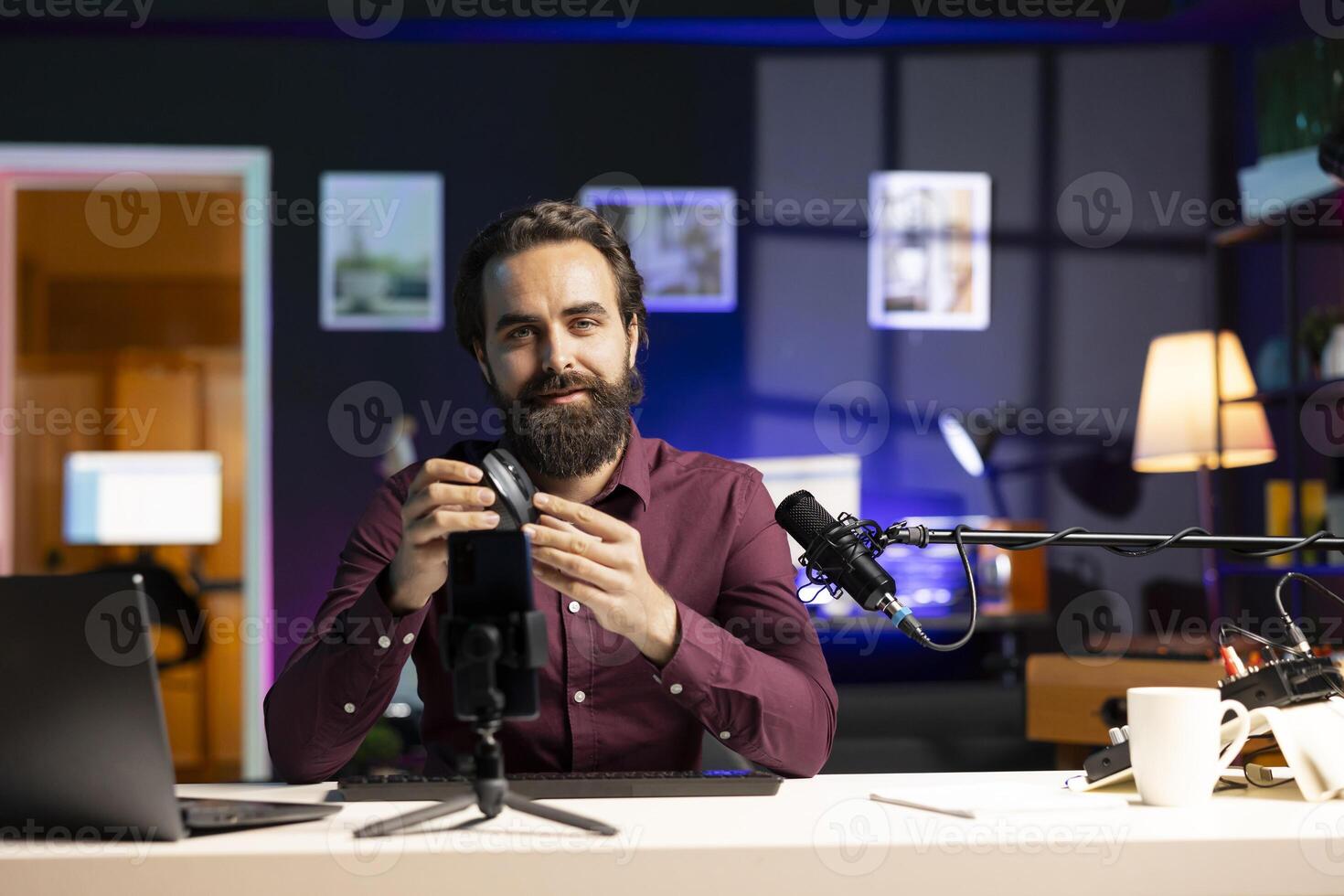 Smiling tech specialist filming review for internet channel in apartment studio, analyzing office mouse for audience. Portrait of content creator endorsing computer peripheral device photo