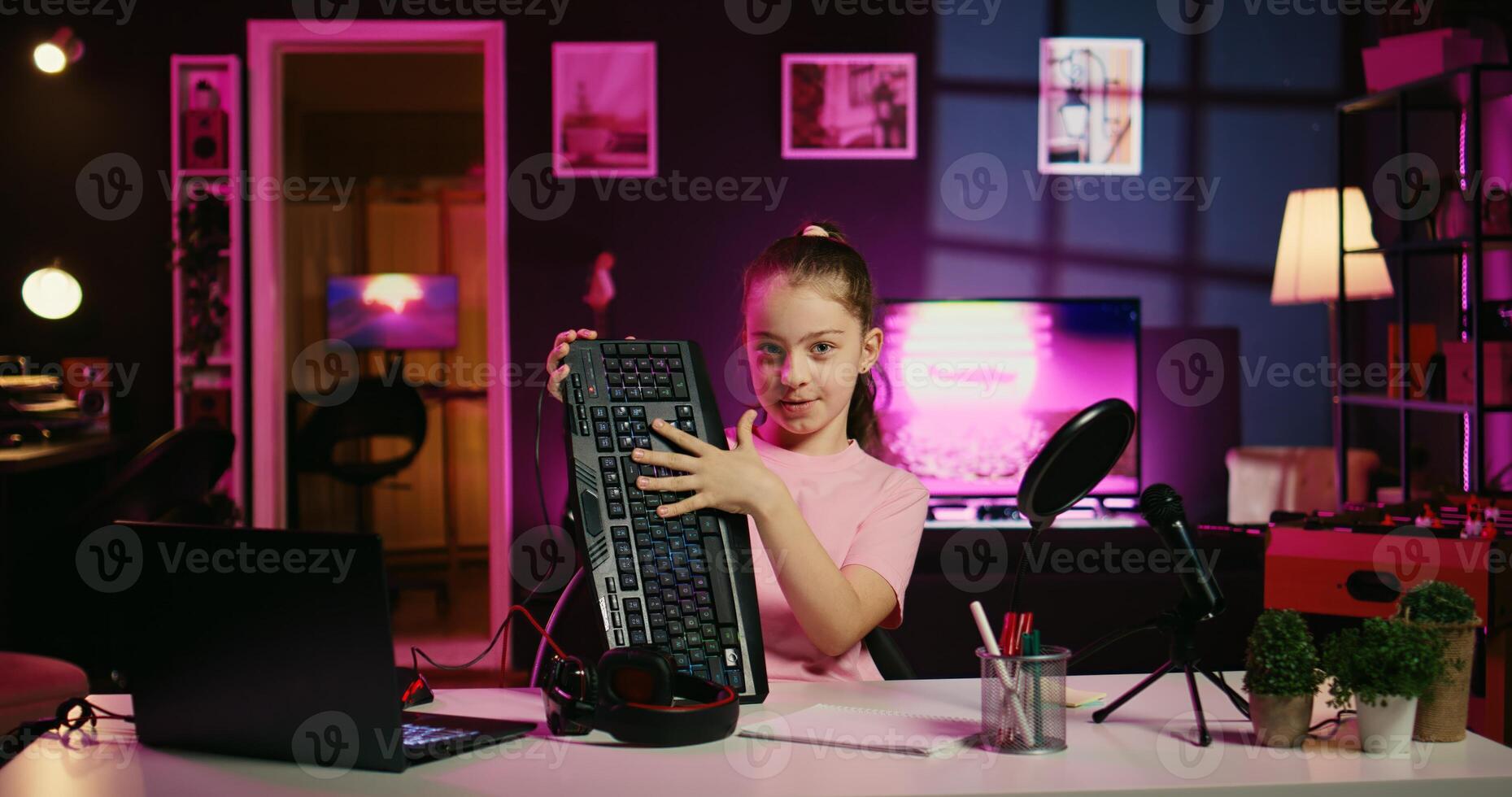 Cute child hosting internet show promotes wireless keyboard and mouse received from sponsoring brand. Little girl does influencer marketing, urging fans to purchase computer peripherals photo