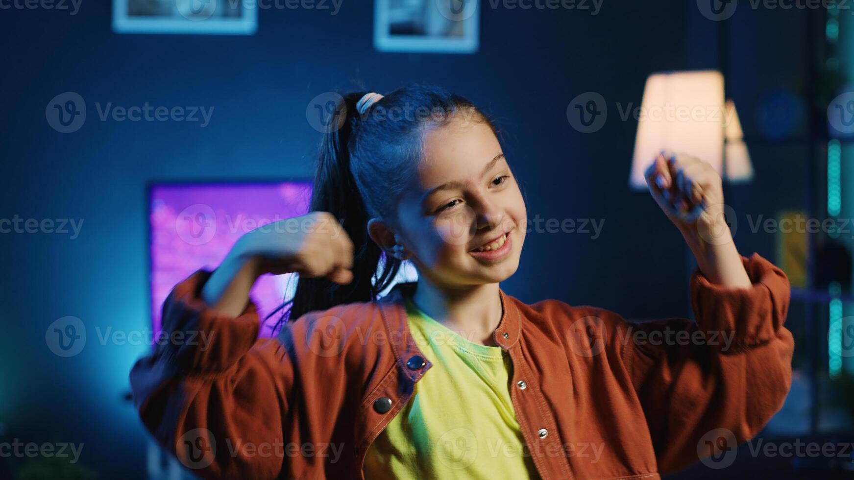 Close up shot on small girl taking part in trends by sharing content of her performing viral choreography on popular hit song. Smiling young internet star doing trending dance moves photo