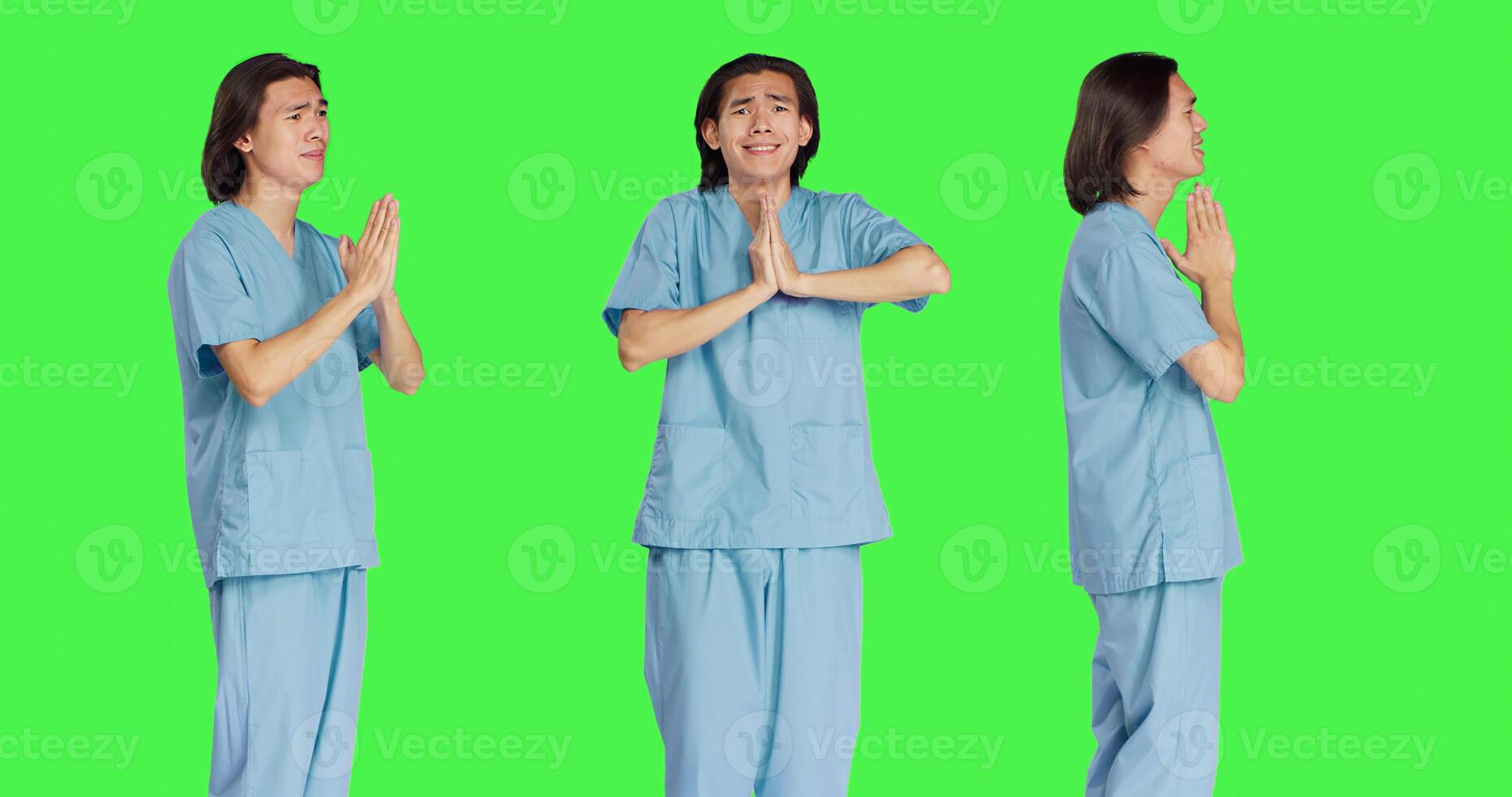 Medical assistant praying to Jesus in studio, holding hands in a prayer while he stands against greenscreen background. Young male nurse with spiritual belief, showing hope. photo