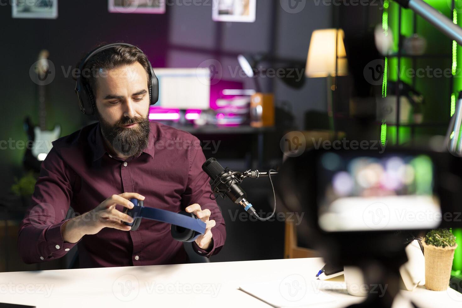 Audiophile reviewing newly launched wireless headphones, filming with professional camera. Tech expert recording internet channel using specialized gear, checking listening device features photo
