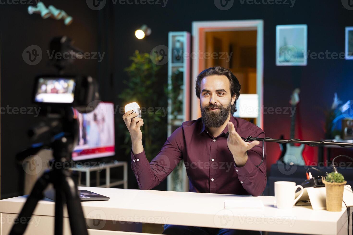 Influencer in dimly lit apartment studio filming smart light bulb review for online streaming platforms with professional camera. Internet star films IoT home automation product with specialized gear photo
