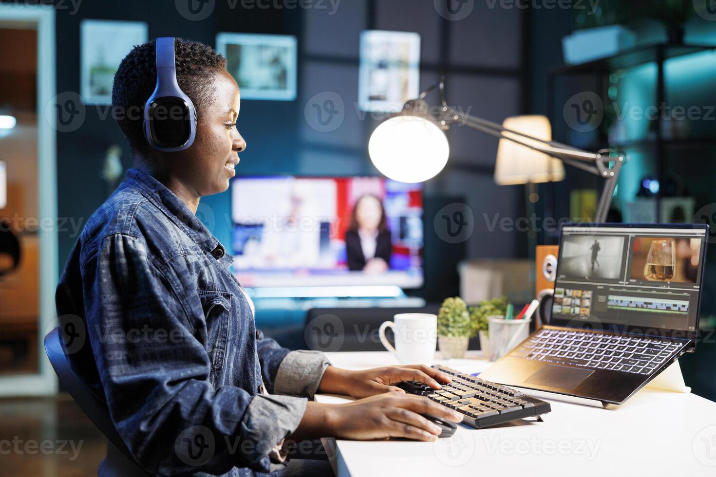 Black woman immersed in world of technology, wearing wireless headphones as she edits photos and videos. African american female filmmaker working with footage and sound, editing new project.