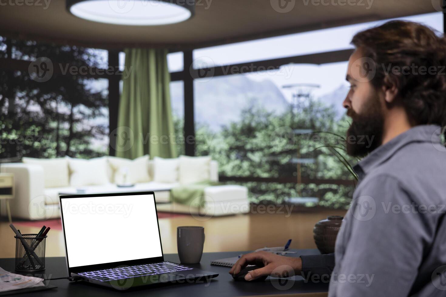 Company leader works with white display template on computer, getting cozy inside his opulent forest villa. Influential businessman examining blank copyspace screen on laptop, rich tycoon. photo