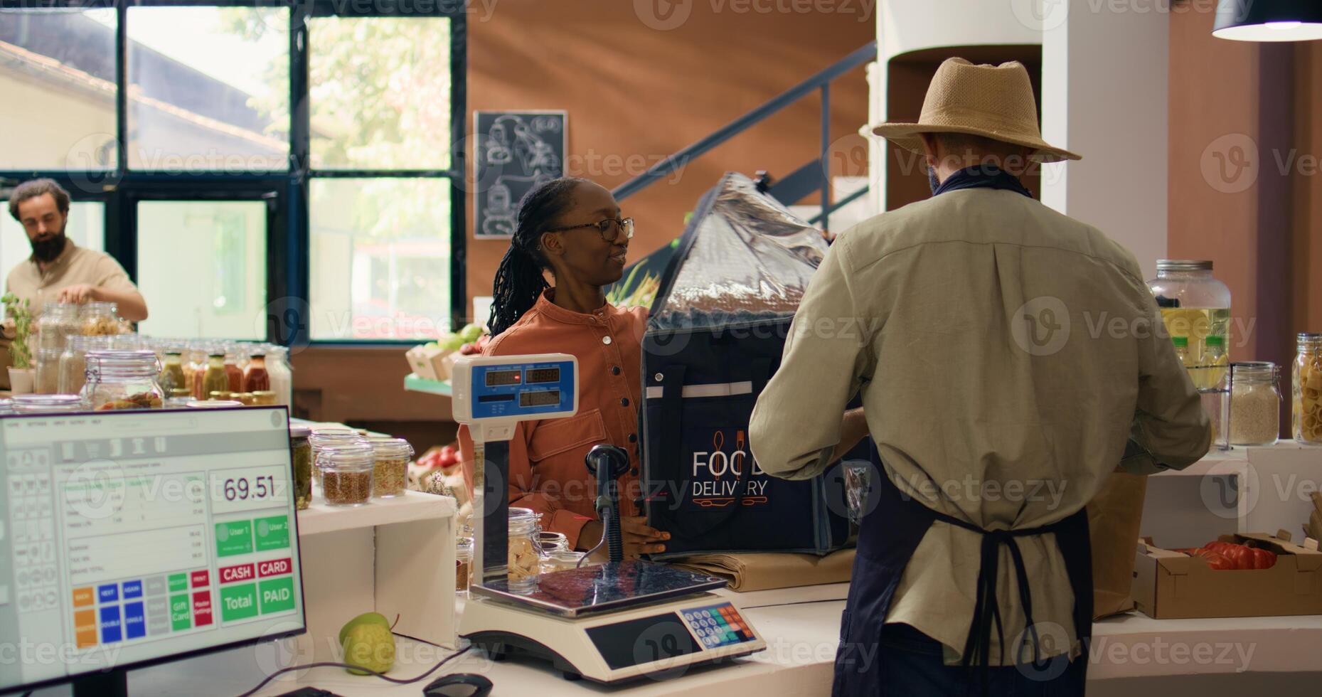 Seller preparing groceries order for home delivery, putting organic produce in backpack. African american employee coming to pick up fruits and vegetables for local eco store customers. photo