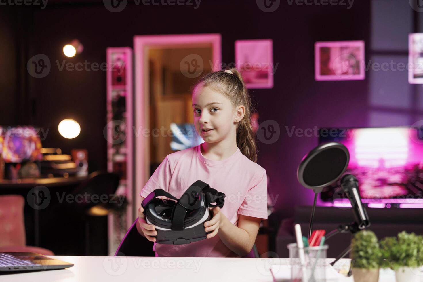 Happy girl films assessing virtual reality technology in headset, talking about components used. Young media star shoots VR goggles review for online channel, pleased with materials quality photo