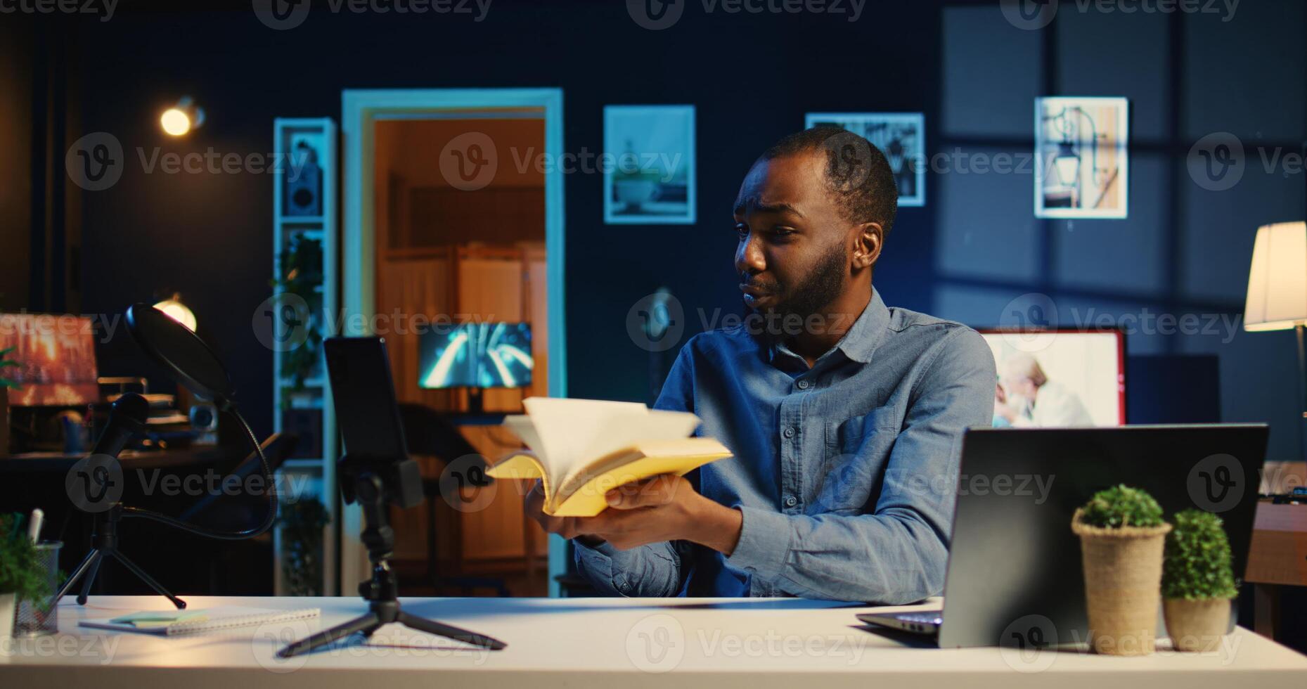 Content creator films review of book using professional camera, presenting synopsis to audience. Media star in cozy apartment studio sponsored by publisher to show new novel release to readers photo