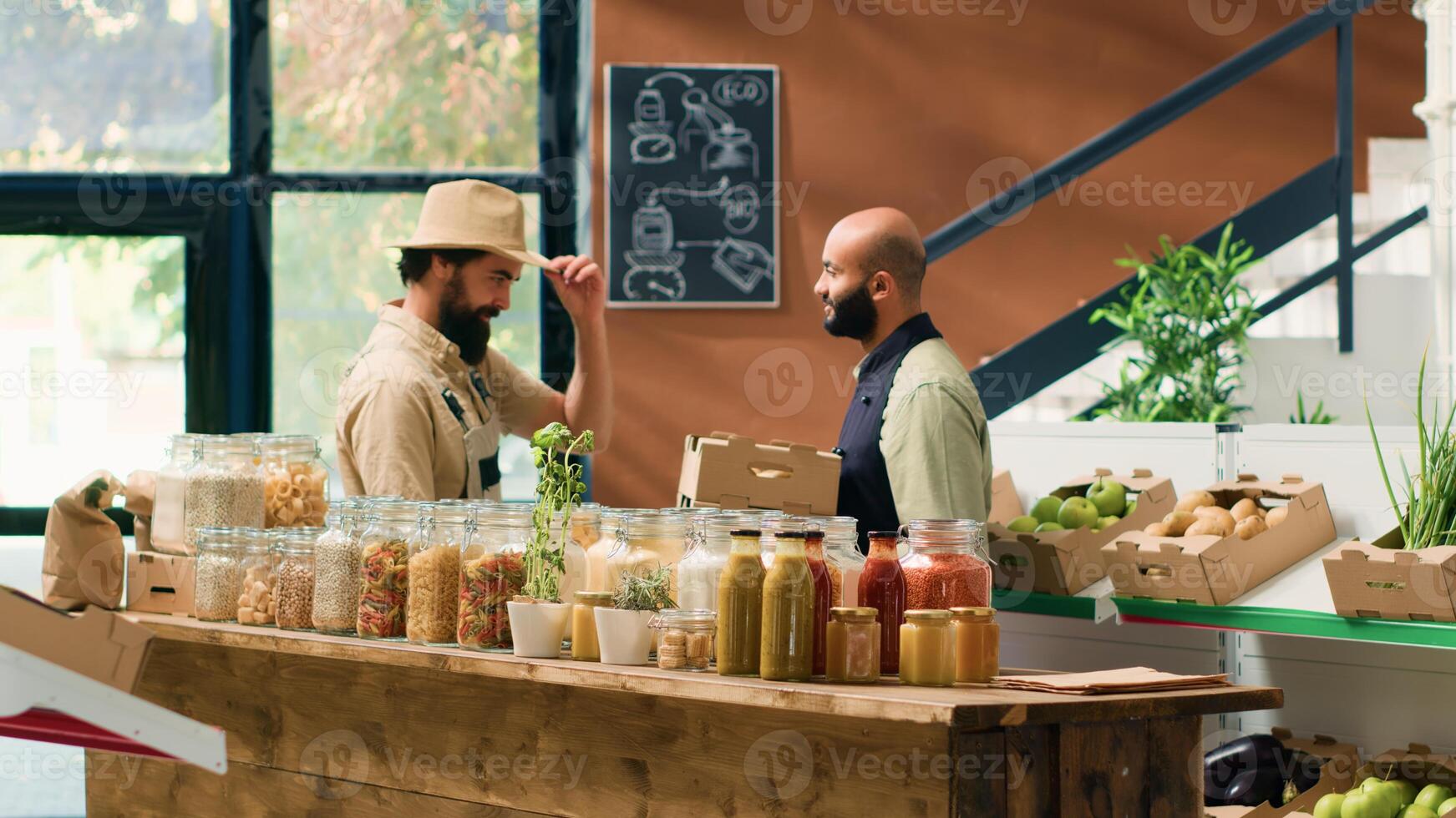 Farmer supplies zero waste eco store with freshly harvested fruits and vegetables, bringing crates filled with new products to local vendor. Storekeeper and farming business owner shake hands. photo