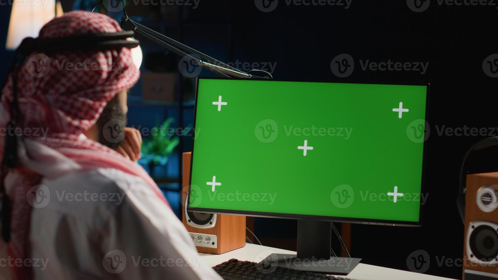 Middle Eastern remote worker inputting data on chroma key computer while working from home. Self employed freelancer performing tasks on mockup device in apartment personal office photo