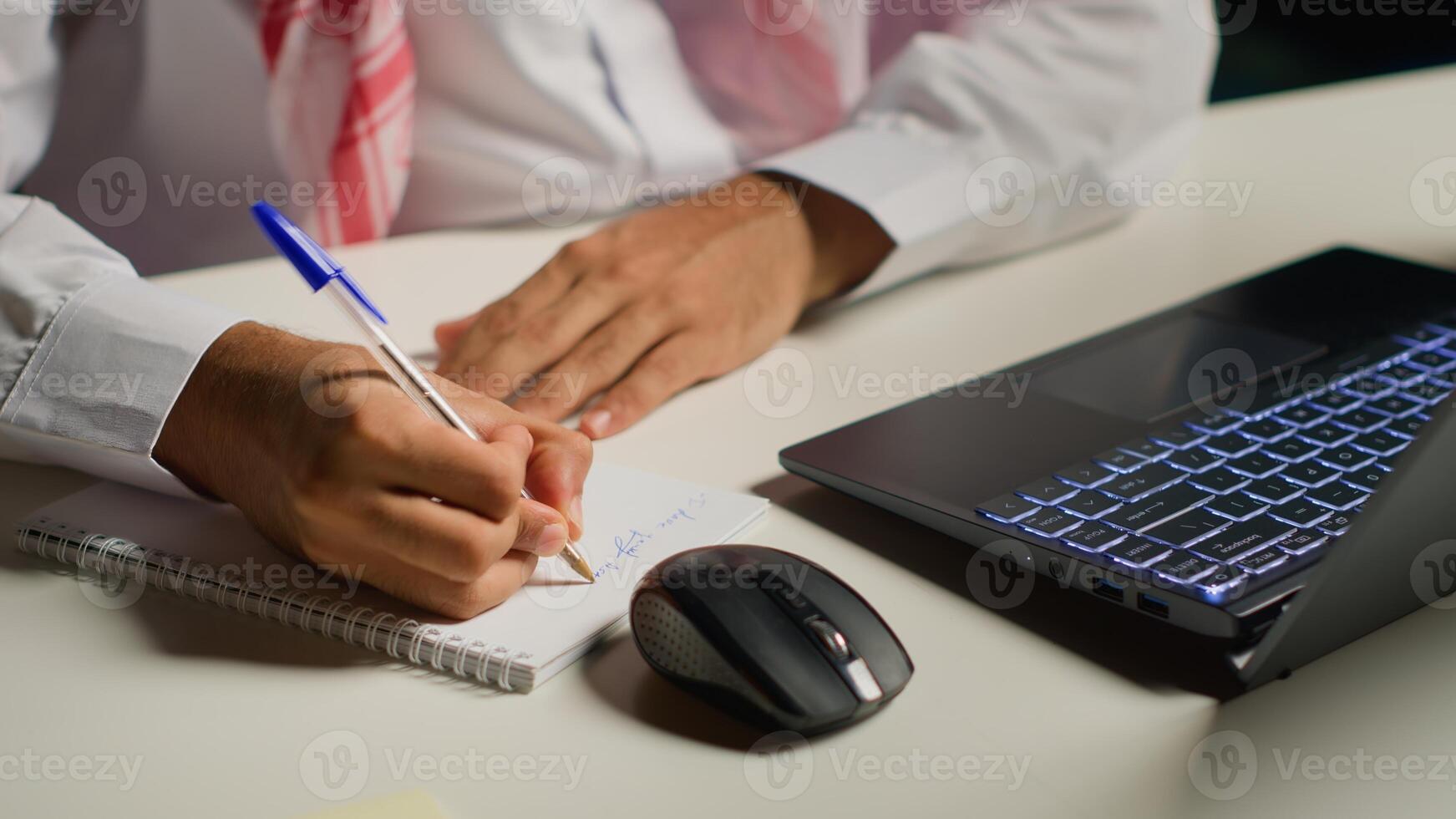 Man at home paying attention in elearning seminar teleconference with teacher, writing on notepad. Homeschooling student listening to lesson while doing his homework tasks photo