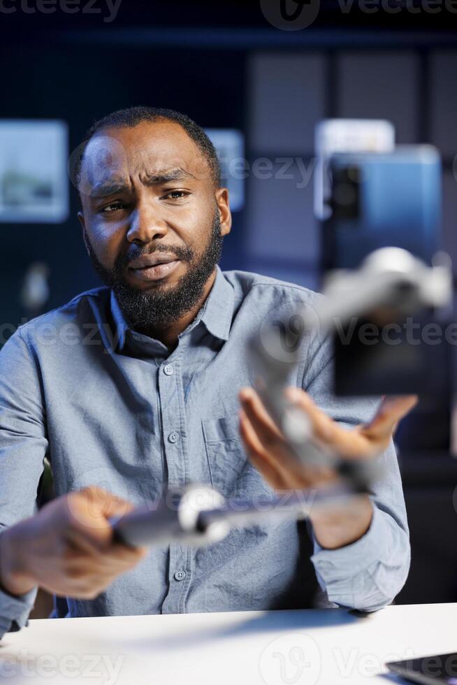 Influencer reviewing selfie stick, expressing dissatisfaction with subpar quality. Content creator shooting for online channel, displeased with low quality smartphone holder photo